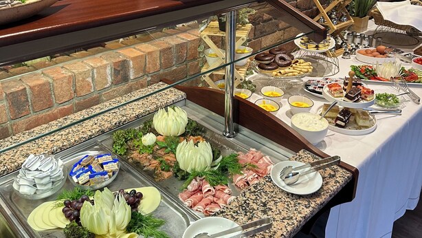 Ein reichhaltiges Buffet mit verschiedenen Speisen und einer Ziegelwand im Hintergrund.