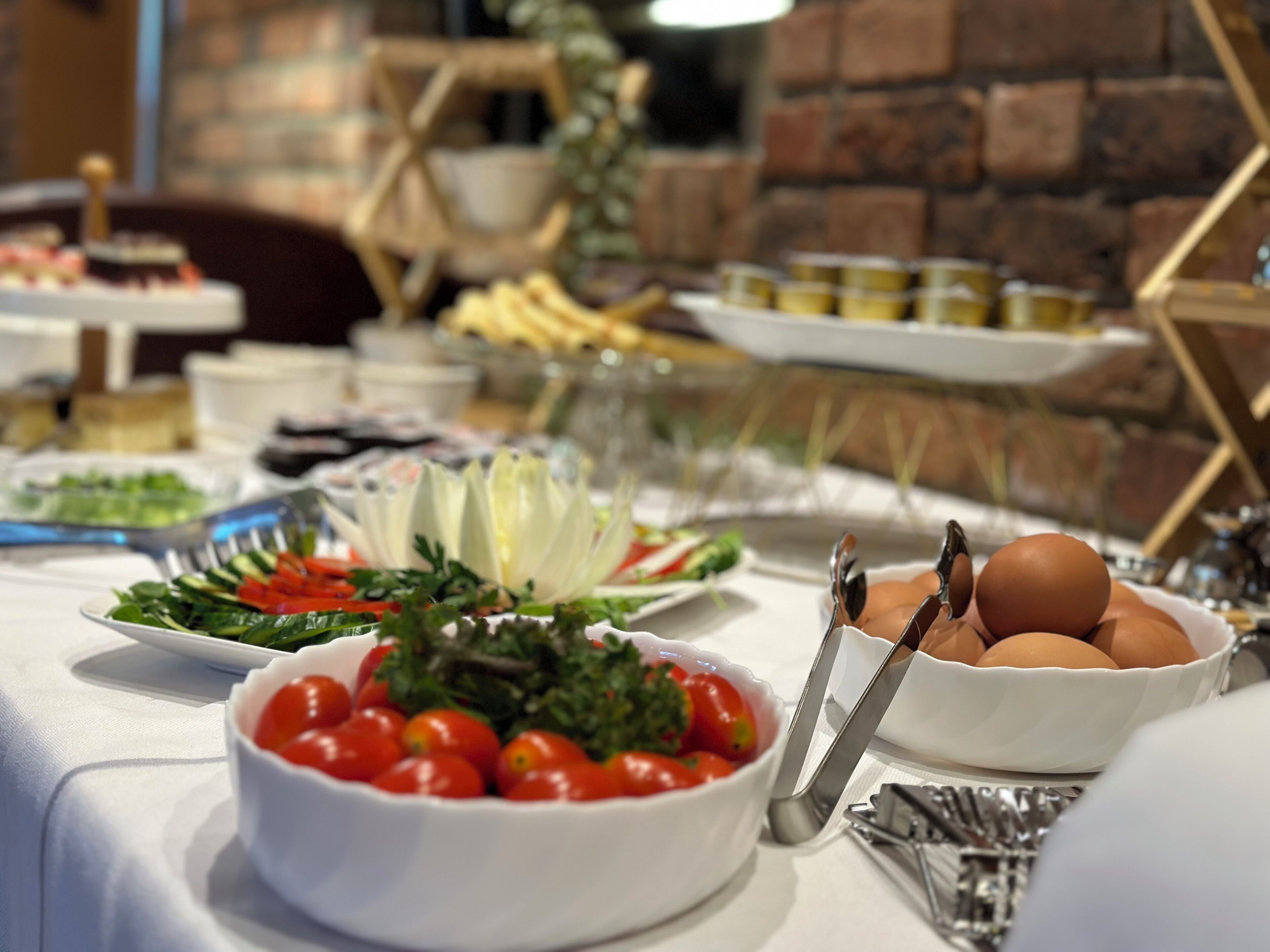 A buffet table with various dishes including salads, fruits, and eggs.