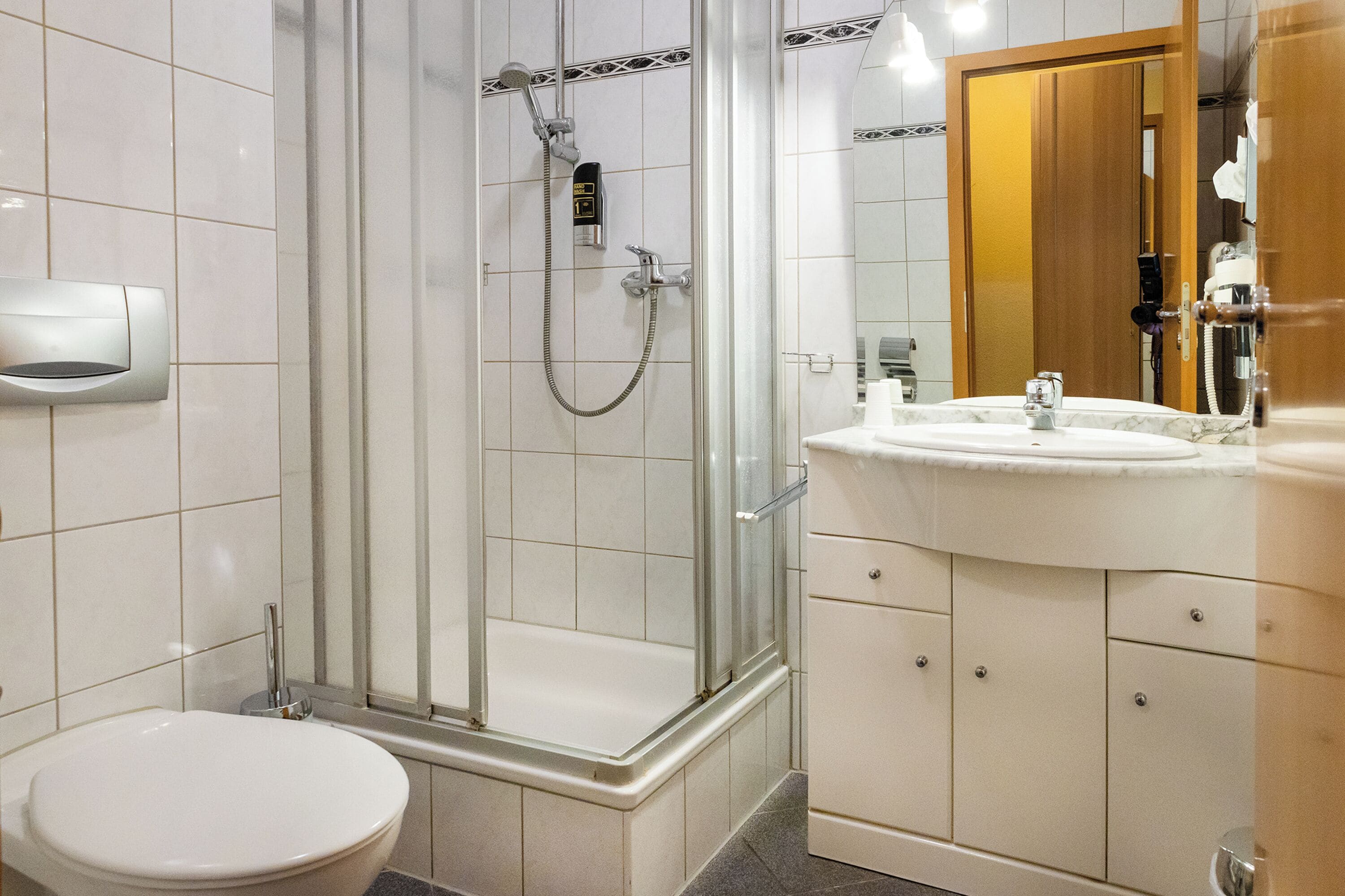 A bathroom with a glass-enclosed shower, a white sink, and a toilet.