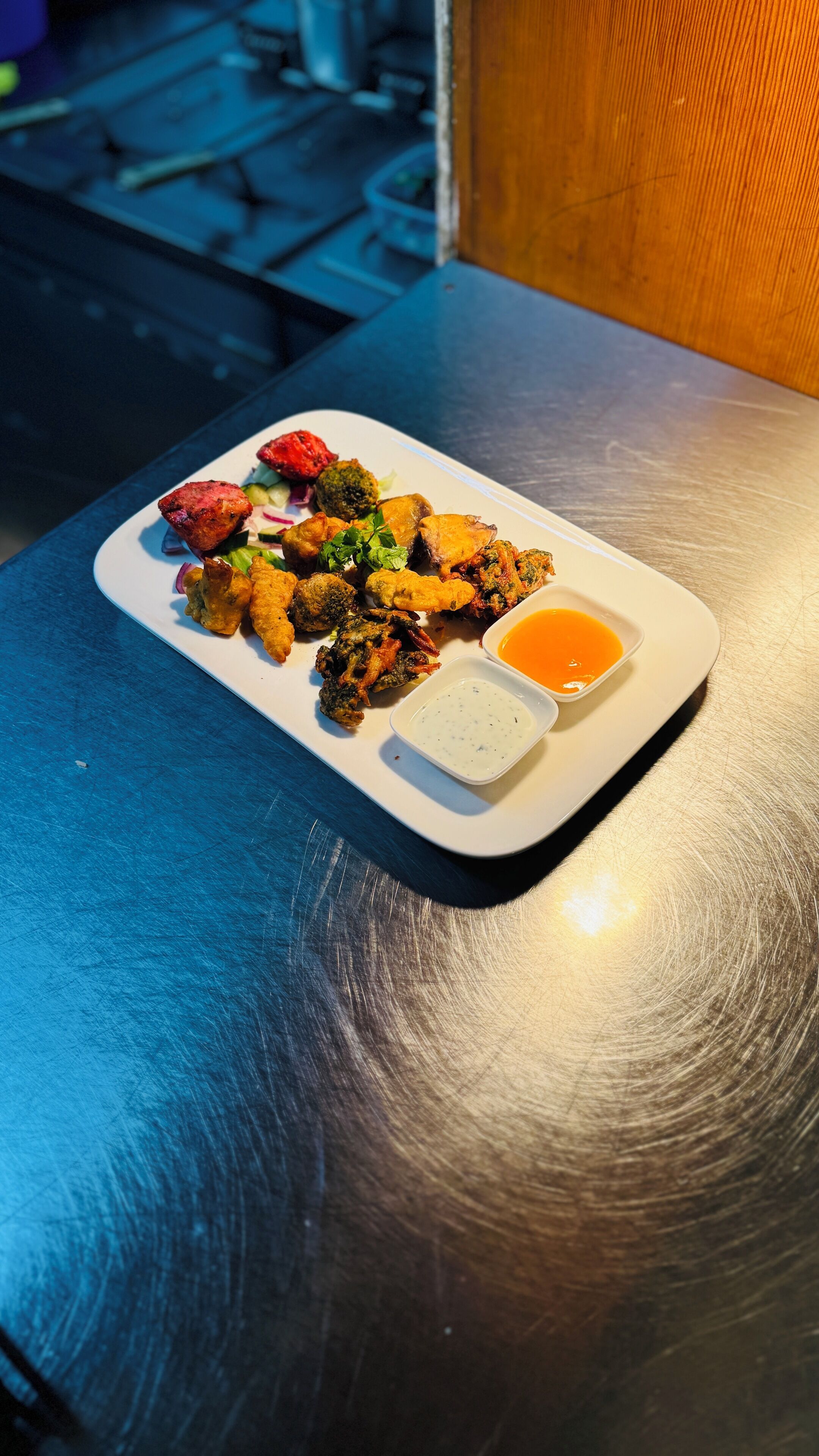 A plate of fried food with two dipping sauces on a table.