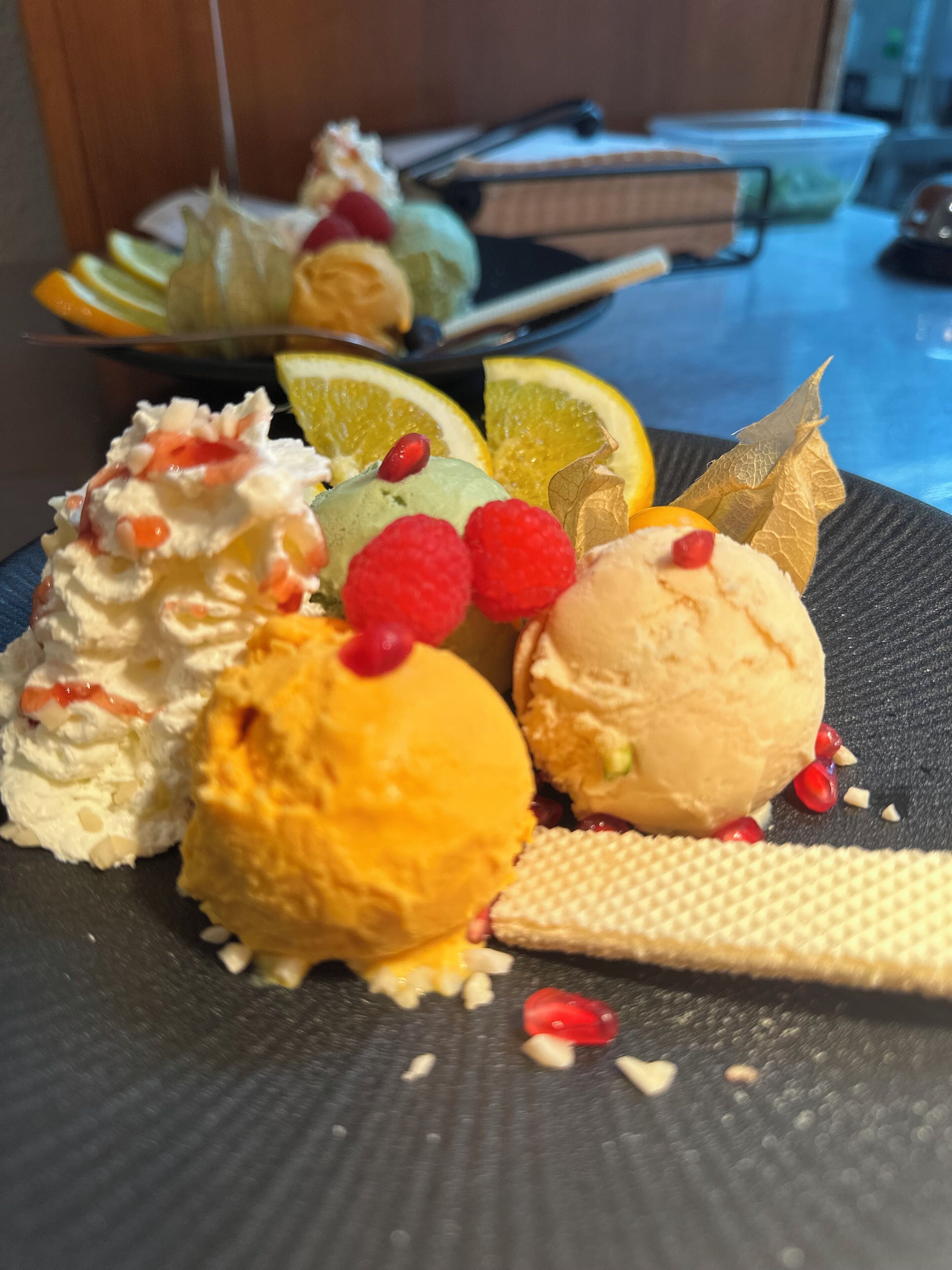 Un plato de postre con diferentes sabores de helado y frutas.