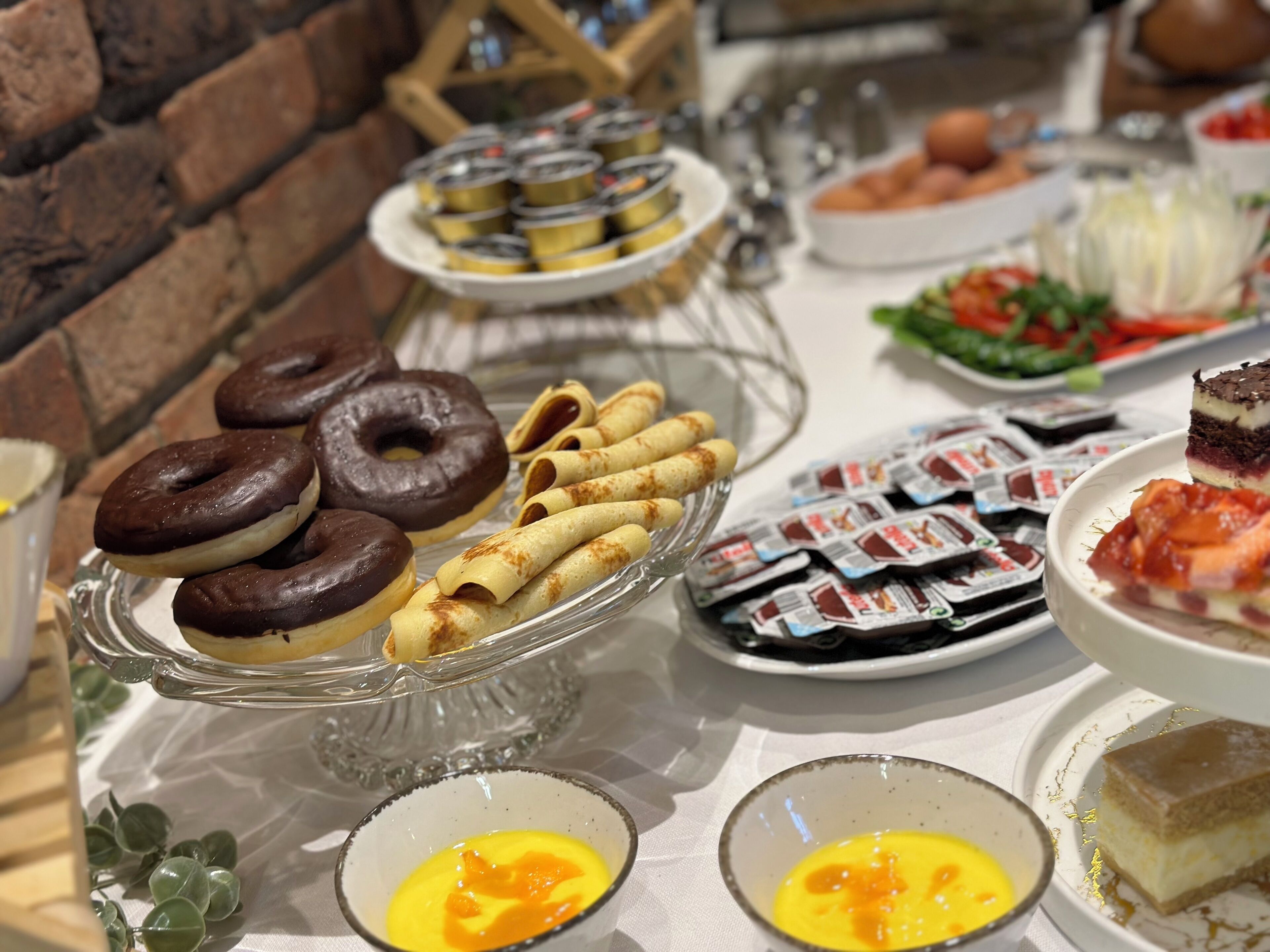 A buffet with various food items including donuts, crepes, and desserts.