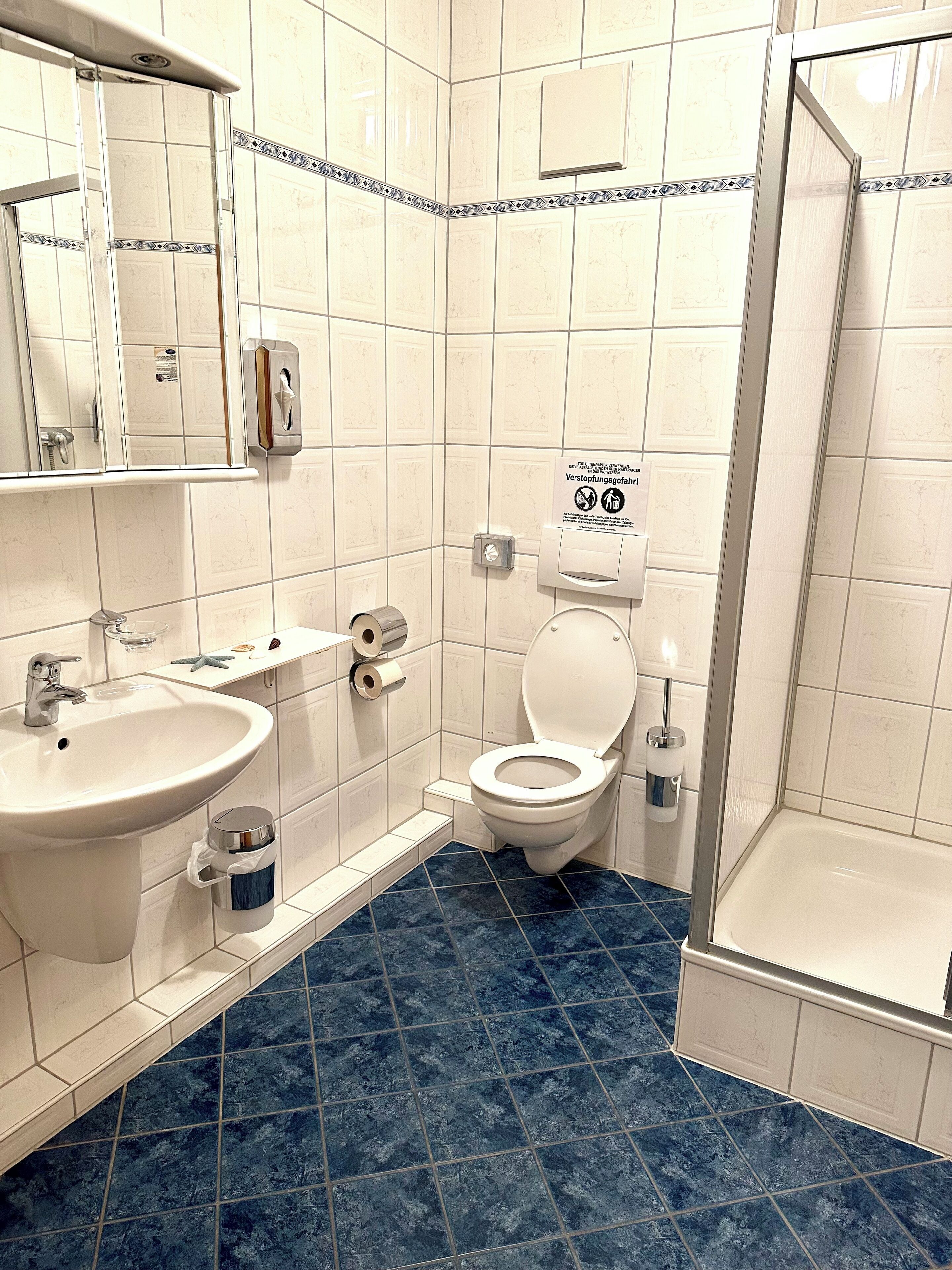 Et badeværelse med vask, toilet og bruser.