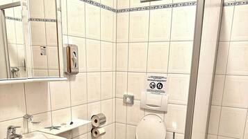 Et badeværelse med vask, toilet og bruser.
