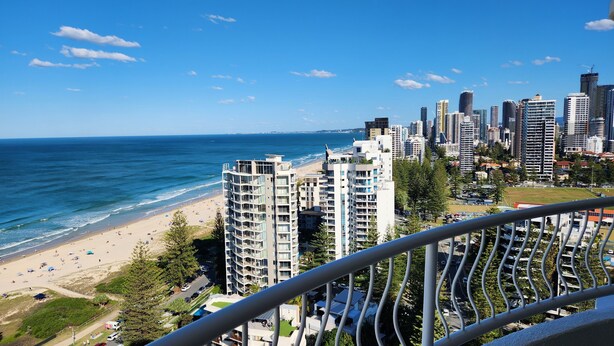 Paisagem costeira com edifícios altos, uma praia e um céu azul límpido.