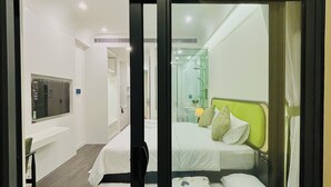 A hotel room with a bed, a TV, a bathroom, and a small rug with cat designs. - S Gen Residences Phu Quoc (Phu Quoc)