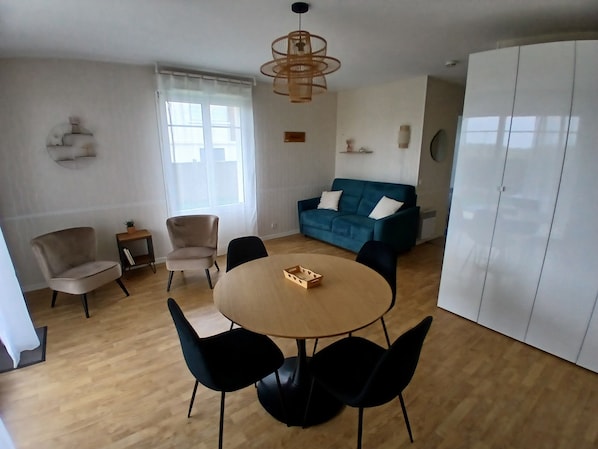 Un salon moderne avec une table ronde en bois, deux canapés et une armoire blanche.