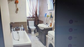 A bathroom with a bathtub, toilet, sink, and washing machine. - Comfortable 1-bedroom apartment, sleeps up to 4, close to marina and nightlife. (QAWRA)
