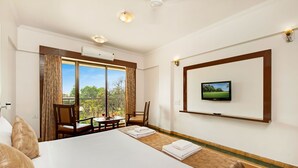 A hotel room with a large bed, a dining table with chairs, a TV mounted on the wall, and a balcony with a view. - Hotel Sapphire  (Mawal)
