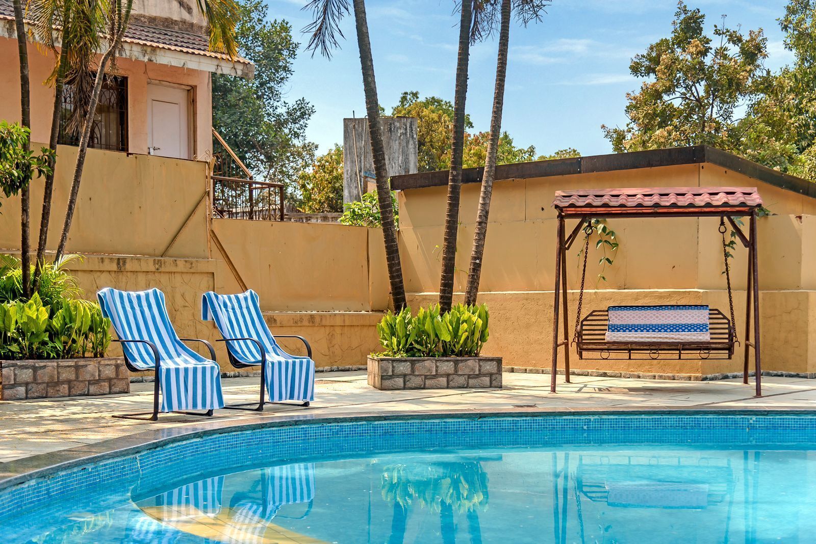 A swimming pool with lounge chairs and a covered seating area.