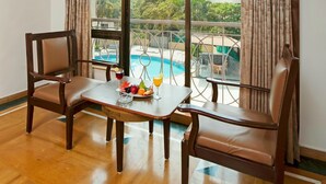 A room with a wooden floor, a dining table with chairs, a window with curtains, and an air conditioning unit. - Hotel Sapphire  (Mawal)