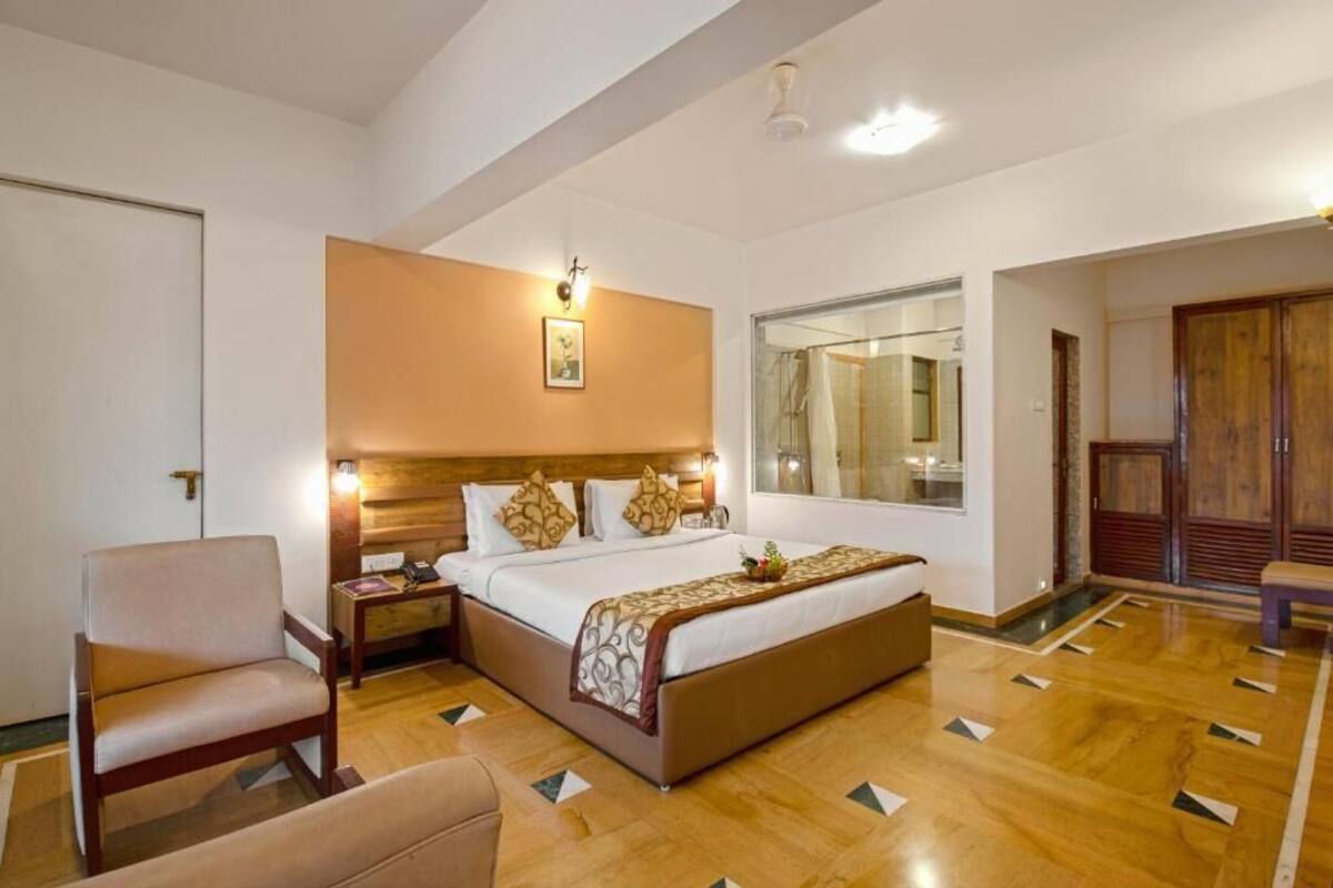 Une chambre d’hôtel avec un grand lit, des tables de chevet, une chaise, un miroir et une armoire.