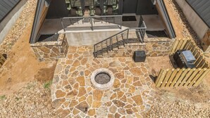 Un patio al aire libre con suelo de piedra, un brasero y una valla de madera.