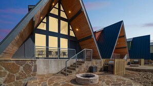 A modern building with a stone exterior, large windows, and a fire pit area.