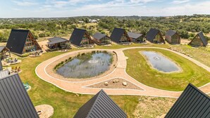 A resort with multiple cabins, a central pond, and a landscaped area with pathways.
