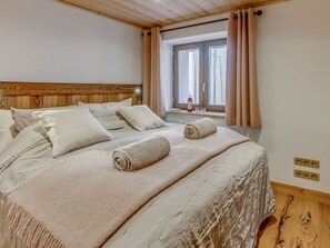 Relax in a spacious bedroom with a large bed and a window with curtains.