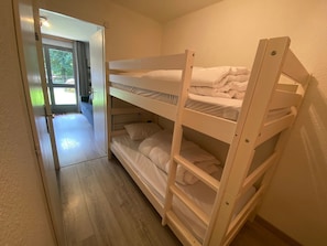 A bunk bed room with a wooden floor and a door leading to a balcony.