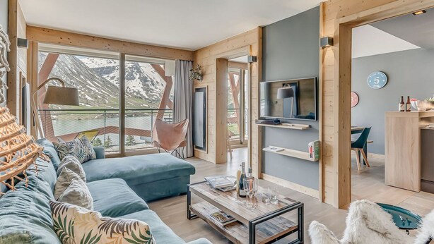 A modern living room with a sofa, a coffee table, a TV, and a dining area with chairs. - Premium 4* Apartment - 5 rooms for 8 people with Wifi (Tignes)