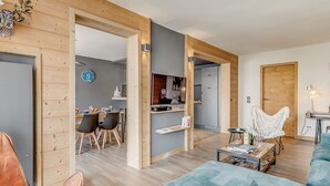 A modern living room with a blue sofa, a leather chair, and a wooden dining area. - Premium 4* Apartment - 5 rooms for 8 people with Wifi (Tignes)