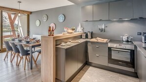 A modern kitchen with a central island, stainless steel appliances, and a dining area with a view. - Premium 4* Apartment - 5 rooms for 8 people with Wifi (Tignes)