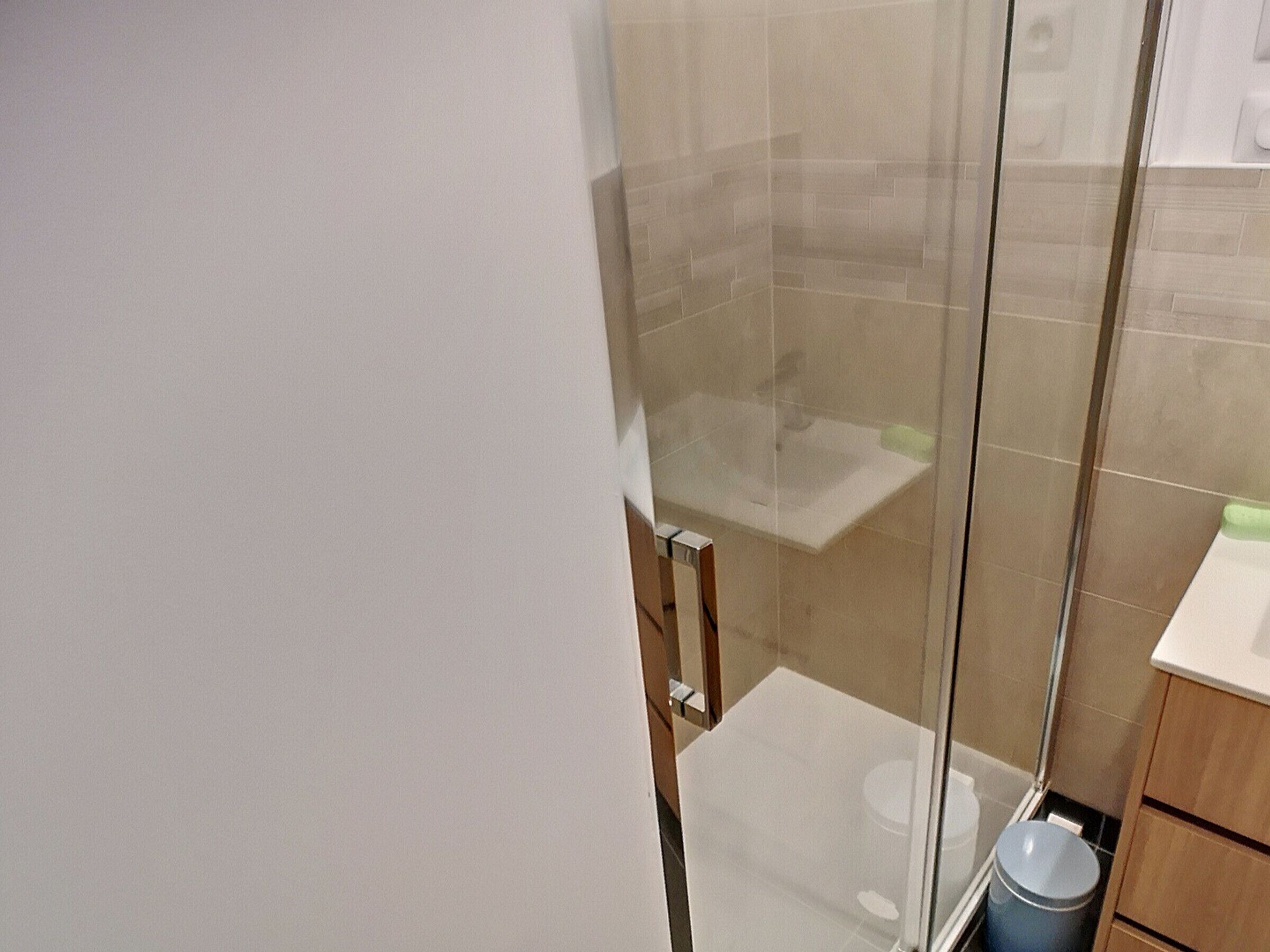Un bagno con box doccia in vetro, un water e un lavandino.