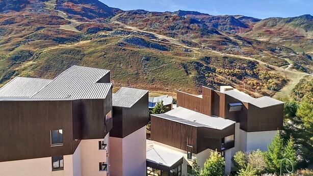 Uma área residencial moderna com edifícios de telhado plano e montanhas ao fundo.