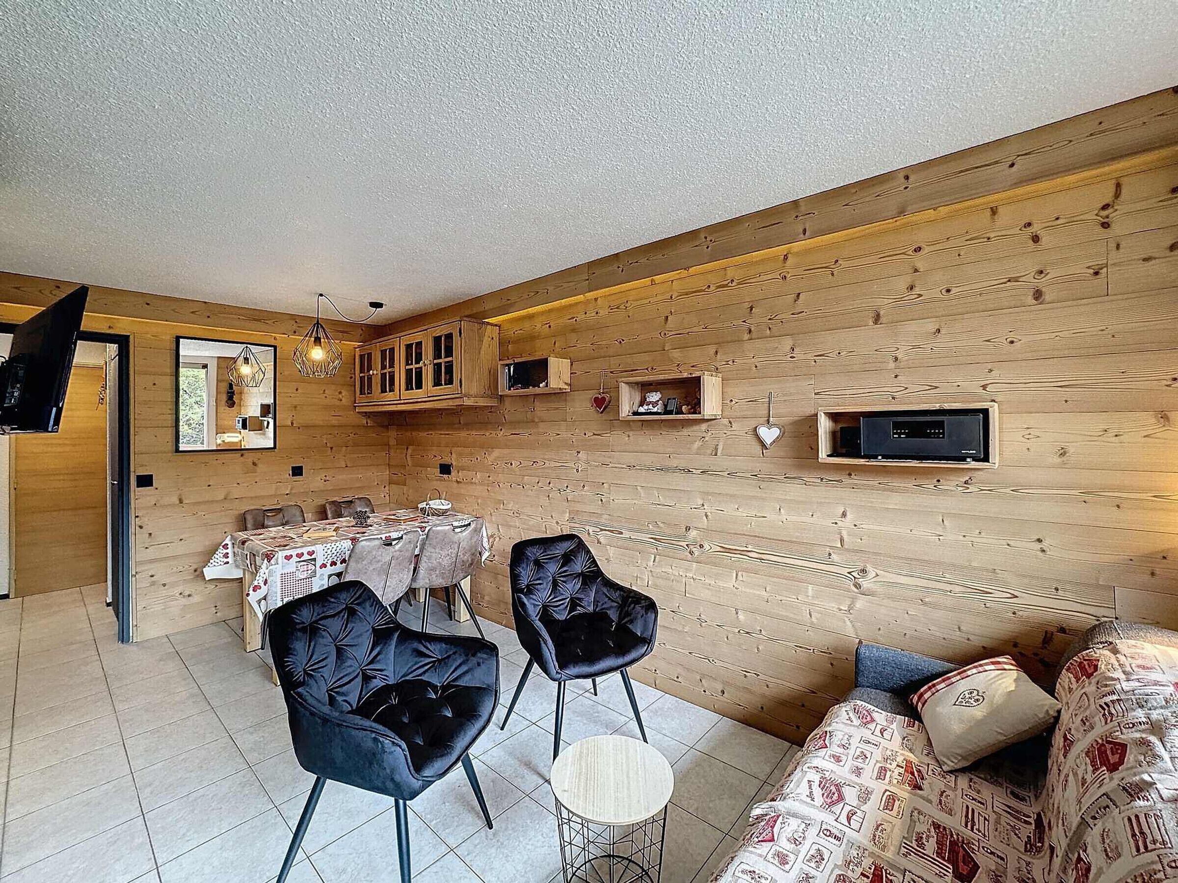 A cozy dining area with a wooden wall, a TV mounted on the wall, and a table set for dining.