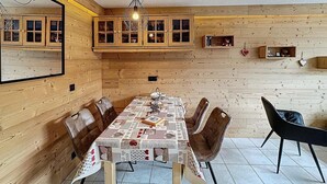 Ruokailutila, jossa on puinen seinä, kattokruunu ja pöytä, joka on katettu kuviollisella pöytäliinalla.
