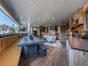 A spacious outdoor area with a long wooden table and benches, a white sofa, and a bar area with a wooden countertop. - Charming apartment with included services in Courchevel (Courchevel)