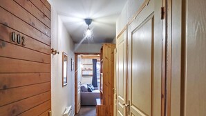 Un pasillo estrecho con paredes de madera, un ventilador de techo y una cama al fondo.