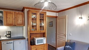 Cocina pequeña con armarios de madera, microondas y cafetera.
