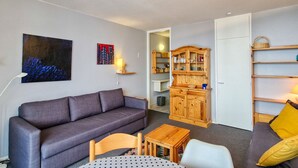 Un salon avec un canapé gris, un meuble en bois et une petite table.