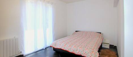 Ein Schlafzimmer mit einem Bett, einem Heizkörper und einem Fenster mit Vorhängen.