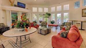 A spacious living room with a round coffee table, a red sofa, and a television on the wall.