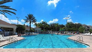 A swimming pool with clear blue water, surrounded by lounge chairs and palm trees.