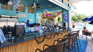 An outdoor bar area with a counter, seating, and a poolside view.