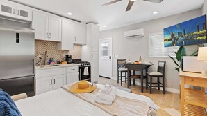 A modern kitchen with white cabinets, a stainless steel refrigerator, and a dining area with a table and chairs.