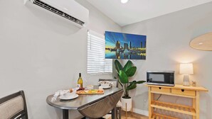 A compact living space with a dining area, a microwave, and a small table with a plant.