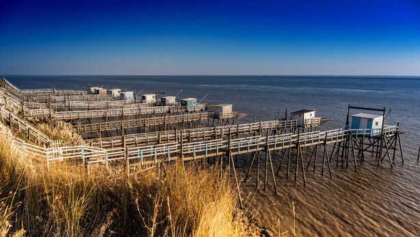 A pier with multiple wooden walkways and small buildings, likely used for fishing or docking boats.