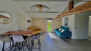 A modern living room with a wooden dining table, two sofas, and a ceiling fan.