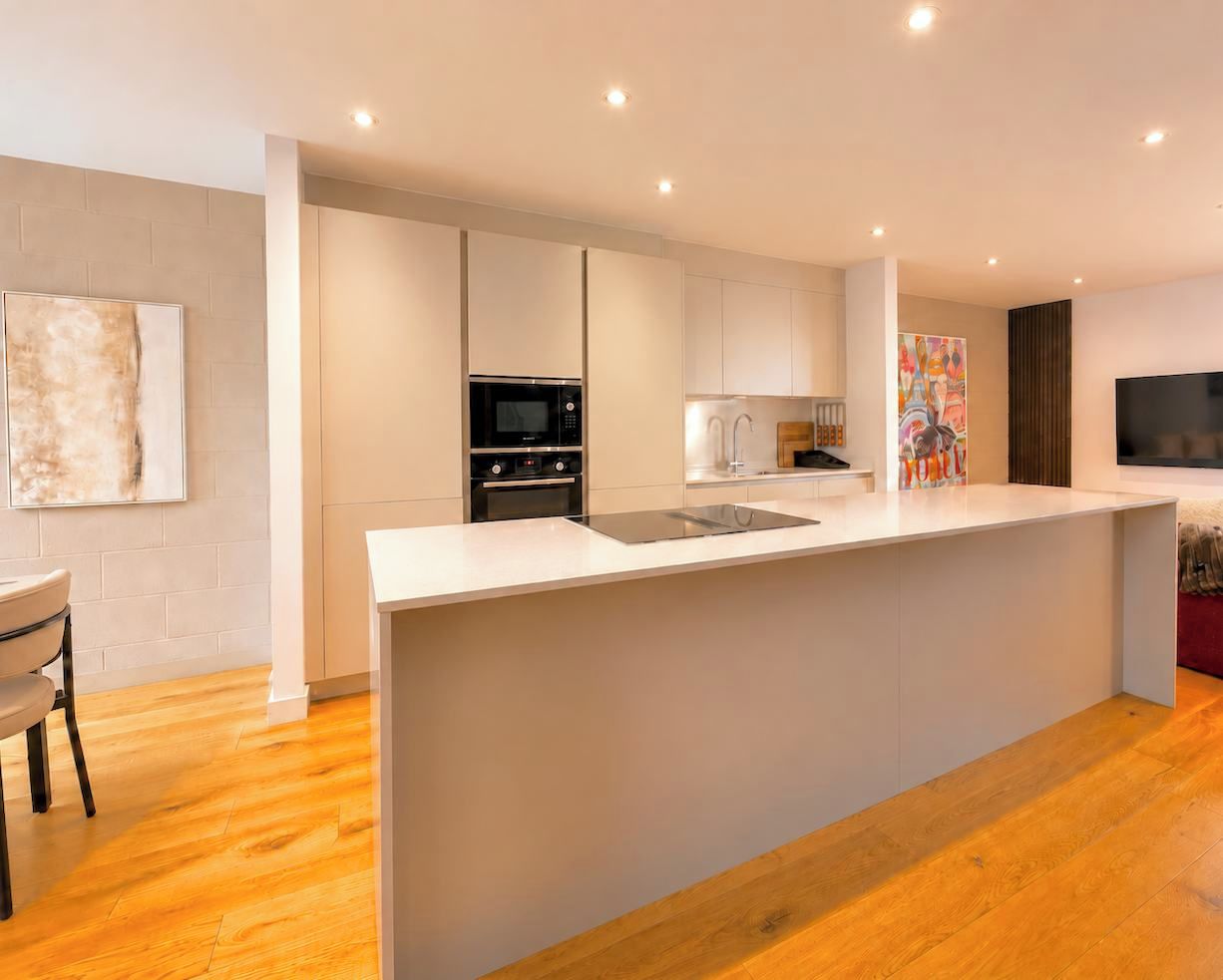 A modern kitchen with a central island, built-in appliances, and a dining area with a chair.