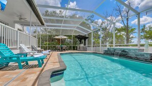 Ein Poolbereich mit überdachter Terrasse, Liegestühlen und einem Wasserfall.
