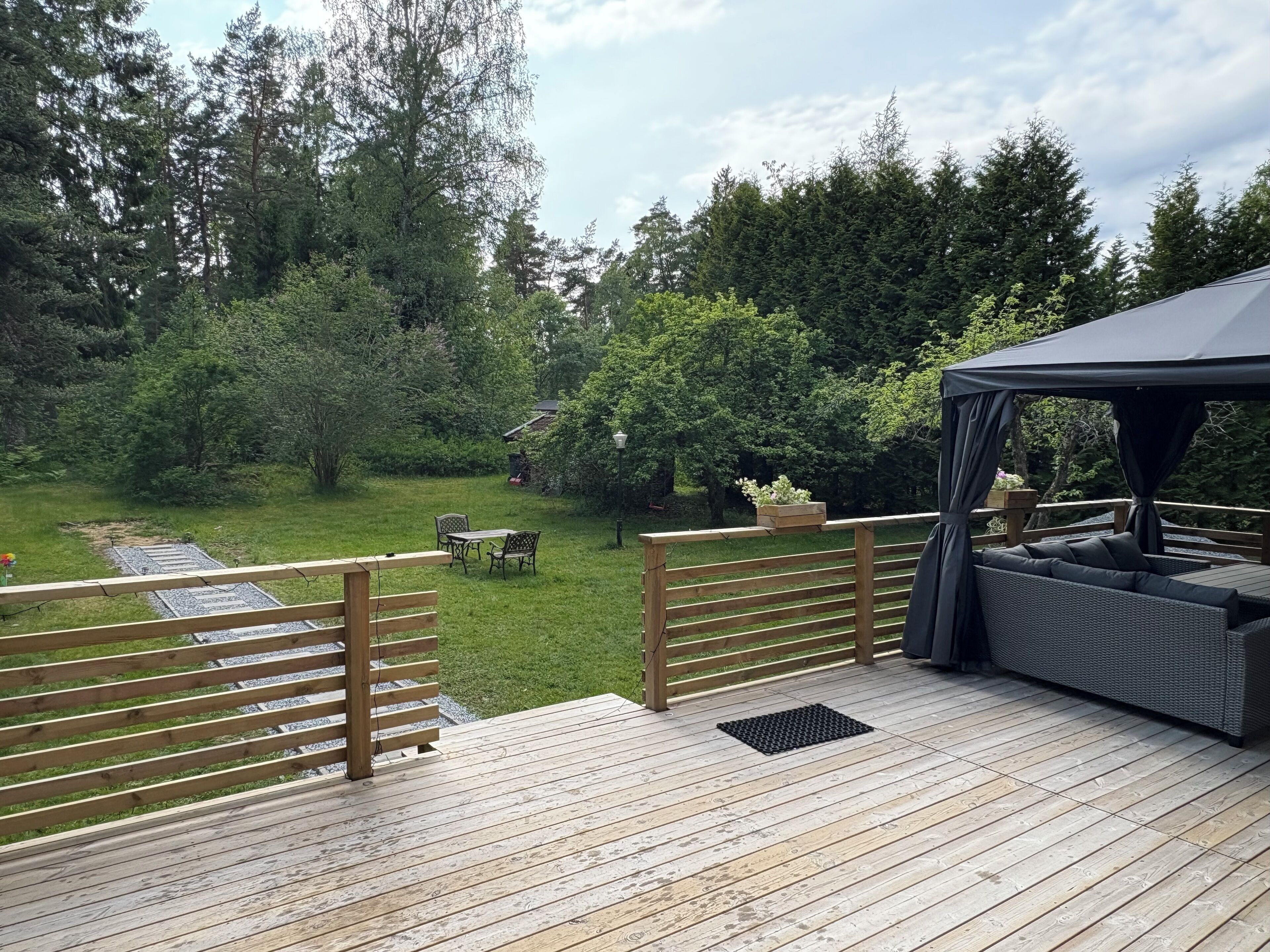 A wooden deck with a covered seating area, a small table, and chairs.