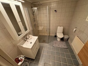 Un baño con ducha, inodoro, lavamanos y espejo.