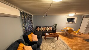 Una sala de estar con un sofá, sillones, una mesa de centro y un comedor con sillas y una mesa.