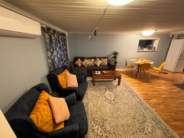 Una sala de estar con un sofá, sillones, una mesa de centro y un comedor con sillas y una mesa.