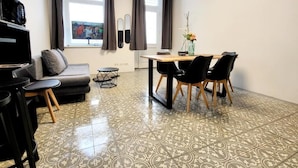 Ein modernes Wohnzimmer mit einer Couch, einem Esstisch mit Stühlen, einem Couchtisch und einem Fernseher.