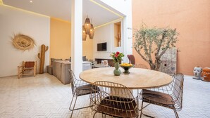 A dining area with a round table, metal chairs, a cactus, and a TV in the background. - Riad Jarco MARRAKECH, heart medina, Rooftop,  Swimmingpool, Near Jemaa El Fna (Marrakech)