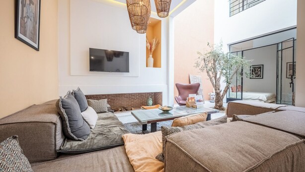 A modern living room with a sofa, a coffee table, and a TV mounted on the wall. - Riad Jarco MARRAKECH, heart medina, Rooftop,  Swimmingpool, Near Jemaa El Fna (Marrakech)