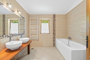 Un baño moderno con dos lavamanos, una bañera y un espejo grande.